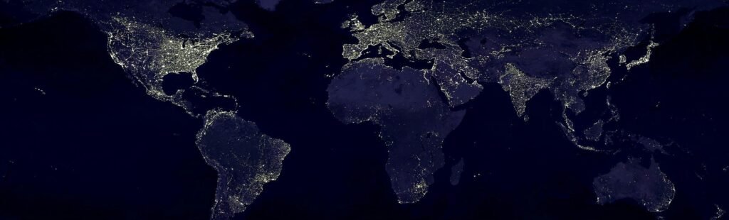 Satellite view of Earth at night with illuminated cities across continents.