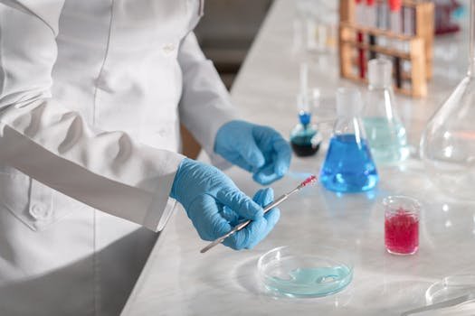 Close-up of a scientist handling samples in a lab with various chemicals and glassware.